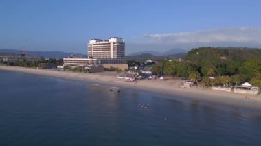 Hız rampası hiperlapse hareket hızı zaman aşımı. Langkawi sahil şeridinin havadan görünüşü, turistlerin berrak mavi suların tadını çıkardığı tropik bir plajdaki otel ve tatil beldelerini gösteriyor.