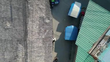 dikey kuşların görüş dronu. Tuk Tuk Tukları 'nın dar bir sokakta ilerleyişinin havadan görüntüsü Güneydoğu Asya' daki dükkanlar ve evlerle dolu.