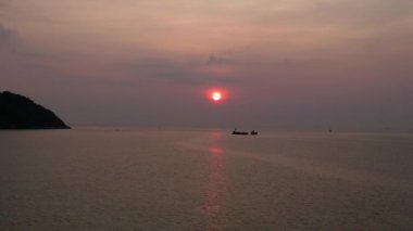 Panorama insansız hava aracı. Günbatımında geleneksel uzun kuyruklu teknelerin bulunduğu tropikal bir sahil manzarası huzurlu ve resimli bir atmosfer yaratıyor.