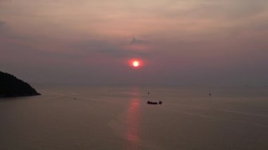 Panorama insansız hava aracı. Günbatımında geleneksel uzun kuyruklu teknelerin bulunduğu tropikal bir sahil manzarası huzurlu ve resimli bir atmosfer yaratıyor.