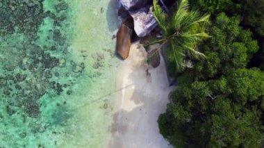 Hız rampası hiperlapse hareket hızı zaman aşımı. Turkuaz su granit kayalar ve yemyeşil tropikal bitki örtüsüyle çevrili kumlu bir sahili nazikçe yıkıyor.
