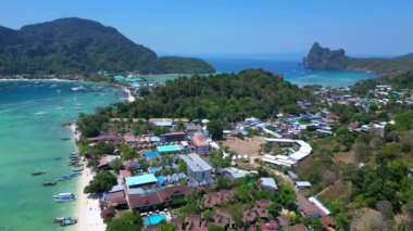 Panorama insansız hava aracı. Turkuaz suyu, tekneleri, lüks otelleri ve dağlık manzaraları olan phi phi adasının havadan görünüşü