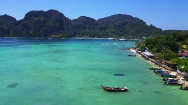 İHA iniyor. Turkuaz suyu, tekneleri, lüks otelleri ve dağlık manzaraları olan phi phi adasının havadan görünüşü