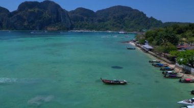 Panorama insansız hava aracı. Turkuaz suyu, tekneleri, lüks otelleri ve dağlık manzaraları olan phi phi adasının havadan görünüşü