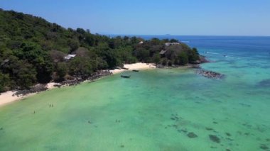 Geri geri uçun. Turkuaz suyu olan tropikal bir adanın havadan görünüşü Tayland 'da turistleri bekleyen uzun kuyruk teknelerini gösteriyor.