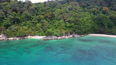 Turkuaz sudaki tekneler, arka planda yemyeşil bir tropik ormanı olan turistlerle dolu beyaz bir kumsal yakınında. panorama yörünge dronu 