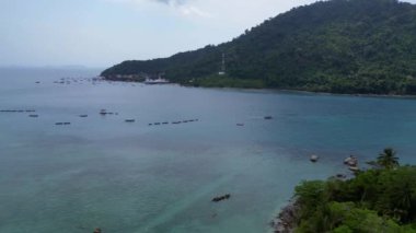 Yeşil enerji üretmek için güneş panelleri kullanan tropik bir ada beldesinin havadan görünüşü. Ters İHA uçuşu 