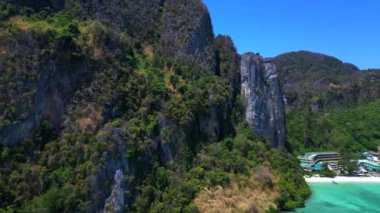 Turkuaz su, doğanın güzelliğini gösteren bir tatil köyü olan tropikal bir adayı çevrelemektedir. Sağ drona döndür 