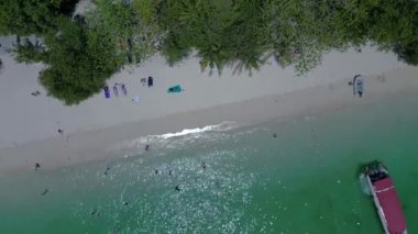 Turkuaz su, doğanın güzelliğini gösteren bir tatil köyü olan tropikal bir adayı çevrelemektedir. dikey kuş bakışı dron 