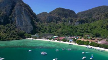 Turistler güneşli bir günde turkuaz suyu ve kireçtaşı kayalıkları olan tropikal bir cennette tekne kullanırlar. Ters İHA uçuşu 