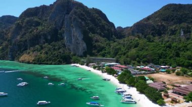 Turistler güneşli bir günde turkuaz suyu ve kireçtaşı kayalıkları olan tropikal bir cennette tekne kullanırlar. panorama yörünge dronu 
