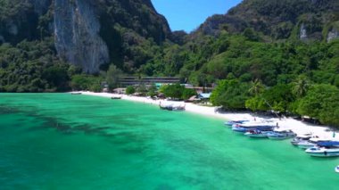 Turistler güneşli bir günde turkuaz suyu ve kireçtaşı kayalıkları olan tropikal bir cennette tekne kullanırlar. geniş yörünge görünümü dronu 