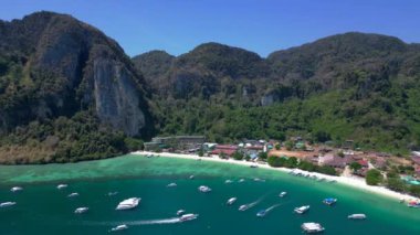 Turistler güneşli bir günde turkuaz suyu ve kireçtaşı kayalıkları olan tropikal bir cennette tekne kullanırlar. geniş yörünge görünümü dronu 