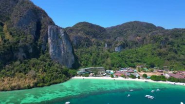 Turkuaz su, doğanın güzelliğini gösteren bir tatil köyü olan tropikal bir adayı çevrelemektedir. panorama yörünge dronu 