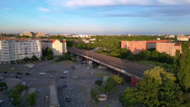 Berlin Innsbrucker Platz 'ın hava görüntüsü. Gün batımında şehir manzarasını kesen yüksek tren rayları var. panorama genel görünüm dronu 