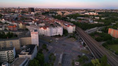 Berlin Innsbrucker Platz 'ın hava görüntüsü. Gün batımında şehir manzarasını kesen yüksek tren rayları var. panorama genel görünüm dronu 