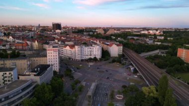 Berlin Innsbrucker Platz 'ın hava görüntüsü. Gün batımında şehir manzarasını kesen yüksek tren rayları var. panorama yörünge dronu 
