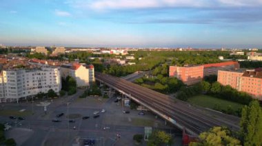 Berlin Innsbrucker Platz 'ın hava görüntüsü. Gün batımında şehir manzarasını kesen yüksek tren rayları var. İHA yükseliyor 