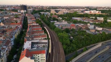 Berlin Innsbrucker Platz 'ın hava görüntüsü. Gün batımında şehir manzarasını kesen yüksek tren rayları var. Ters İHA uçuşu 