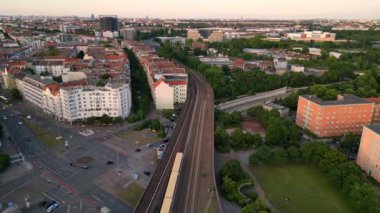 Berlin Innsbrucker Platz 'ın hava görüntüsü. Gün batımında şehir manzarasını kesen yüksek tren rayları var. panorama genel görünüm dronu 