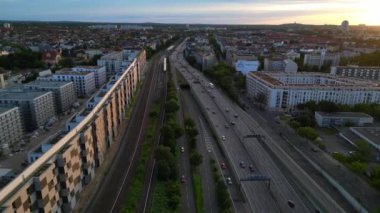 Berlin 'de gün batımında bir tren ve arabalarla geçen bir otobanın görüntüsü. Ters İHA uçuşu 