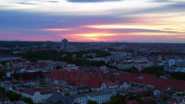 Güneş, Berlin şehrinin üzerinde batıyor. Binalara, Funkturm Kulesi 'ne ve aşağıdaki sokaklara sıcak bir ışıltı saçıyor. panorama genel görünüm dronu 