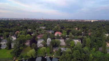 Berlin şehri sakin bir gölün kıyısında doğayla kusursuz bir şekilde harmanlanıyor. Kentsel gelişim ve çevresel korunmanın uyumlu bir arada yaşaması. panorama genel görünüm dronu 