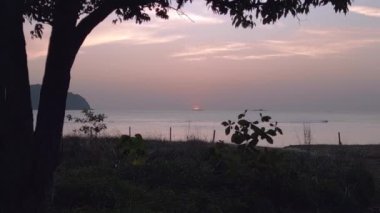 Güneş sakin okyanusun üzerinde batar, sıcak renklerle gökyüzünü boyar. Bulutlar canlı renkleri yansıtır, sakin bir deniz manzarası yaratır. uçuş üstü insansız hava aracı 