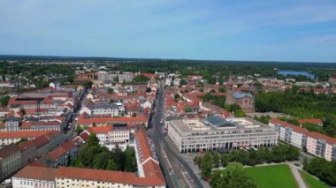 Güneşli ve bulutlu bir günde etrafını çevreleyen kırmızı çatıları ve yeşil ağaçları olan Potsdam şehir merkezinin hava manzarası. Ters İHA uçuşu 