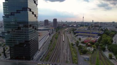 Berlin İstasyonu 'nun modern mimarisi ve tren raylarıyla bulutlu bir yaz gününde şehir merkezine giden hava manzarası. panorama genel görünüm dronu 