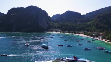 Phi phi Adası Tonsai rıhtımında turkuvaz suya yanaşmış tekneler ve güneşli bir günde Tayland 'da yürüyen turistler. panorama genel görünüm dronu 