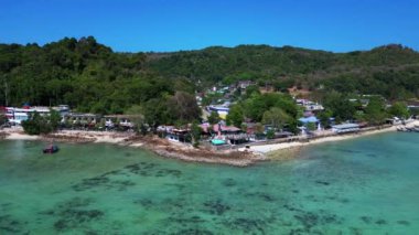 Phi phi adası korsanları plaj koyunda turkuaz sularda kayıklar ve güneşli bir günde Tayland 'da yürüyen turistler. panorama yörünge dronu 
