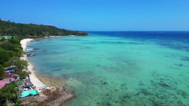 Phi Phi adası korsanları plaj koyunda turkuvaz suya yanaşmış tekneler ve güneşli bir günde Tayland 'da yürüyen turistler. panorama yörünge dronu 