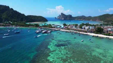Phi phi Adası Tonsai rıhtımında turkuvaz suya yanaşmış tekneler ve güneşli bir günde Tayland 'da yürüyen turistler. İticileri ileri çalıştır 