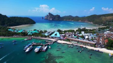 Phi phi Adası Tonsai rıhtımında turkuvaz suya yanaşmış tekneler ve güneşli bir günde Tayland 'da yürüyen turistler. İHA alçalıyor 