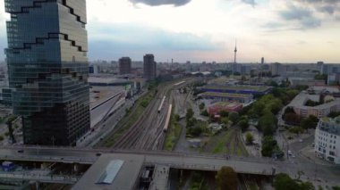 Berlin İstasyonu 'nun modern mimarisi ve tren raylarıyla bulutlu bir yaz gününde şehir merkezine giden hava manzarası. Dolly sol İHA 