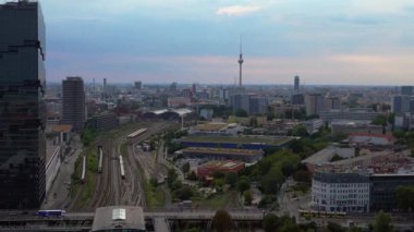 Berlin Warschauer köprü istasyonu, birden fazla tren yolu, modern gökdelenler ve arka planda ikonik televizyon kulesi. panorama genel görünüm dronu 