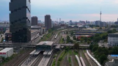 Berlin Warschauer istasyonu, birden fazla tren yolu, modern gökdelenler ve arka planda ikonik televizyon kulesi. doly sağ drone 