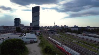 Berlin Warschauer istasyonu, birden fazla tren yolu, modern gökdelenler ve arka planda ikonik televizyon kulesi. Yukarıdan insansız hava aracı görüntüleri 