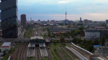 Berlin Warschauer köprü istasyonu, birden fazla tren yolu, modern gökdelenler ve arka planda ikonik televizyon kulesi. Yukarıdan insansız hava aracı görüntüleri 