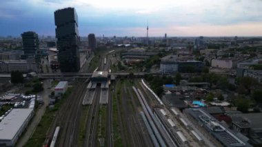Berlin Warschauer istasyonu, birden fazla tren yolu, modern gökdelenler ve arka planda ikonik televizyon kulesi. İHA alçalıyor 