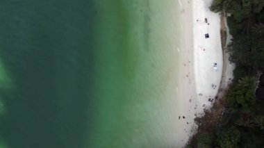 Turistler, Malezya 'daki yemyeşil tropikal ormanlarla kumlu kafatası sahillerinde dinleniyorlar. Yukarıdan aşağıya doğru uçur 
