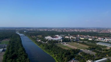 Güneşli bir yaz gününde Rb Leipzig 'e ev sahipliği yapan bir arenanın hava manzarası yemyeşil çevreyi ve şehir manzarasını gözler önüne seriyor. geniş yörünge görünümü dronu 