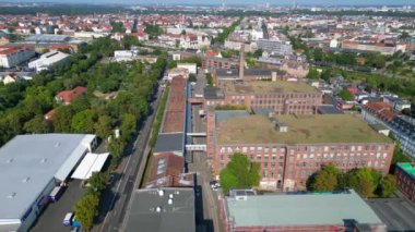 Hava perspektifi Leipzig pamuk fırıldak fabrikası endüstriyel mimarisi sergiliyor, tuğla binalar ve belirgin bir bacayla karakterize ediliyor. geniş yörünge görünümü dronu 