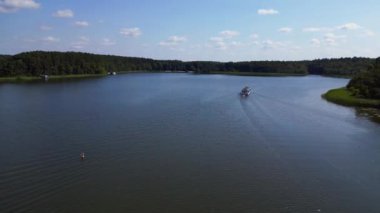 Güneşli bir yaz gününde yeşil ormanlarla çevrili sakin bir göl üzerindeki yolcu feribotunun hava görüntüsü. hız rampası hiper hareket zaman aşımı 
