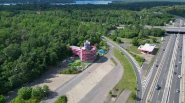Bulutlu bir günde çevresi ormanla çevrili bir otoyolda giden arabalar göle çıkıyor. panorama yörünge dronu 