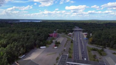 Bulutlu bir günde çevresi ormanla çevrili bir otoyolda giden arabalar göle çıkıyor. uçuş üstü insansız hava aracı 