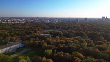 Tiergarten Park 'ın canlı sonbahar yeşillikleri üzerinde yükselen ikonik Berlin zafer sütununun havadan görünüşü. Arka planda şehir manzarası var. hız rampası hiper hareket zaman aşımı 