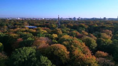 Tiergarten Park 'ın canlı sonbahar yeşillikleri üzerinde yükselen ikonik Berlin zafer sütununun havadan görünüşü. Arka planda şehir manzarası var. hız rampası hiper hareket zaman aşımı 