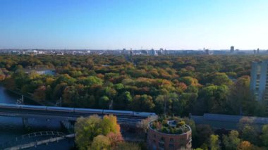 Berlin 'de bir köprüyü geçen trenin manzarası. Etrafı canlı sonbahar yapraklarıyla çevrili. Yukarıdan insansız hava aracı görüntüleri 